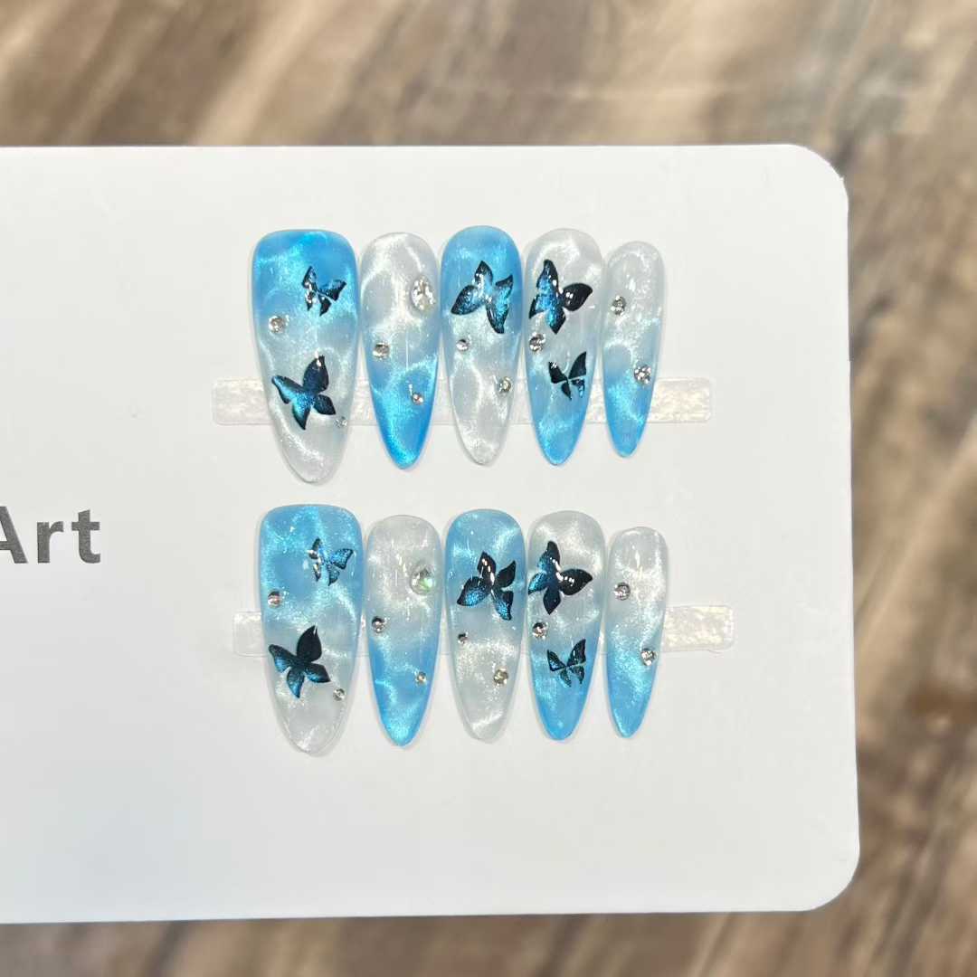 Ice blue cat-eye press-on nails with black butterfly art and French gradient
